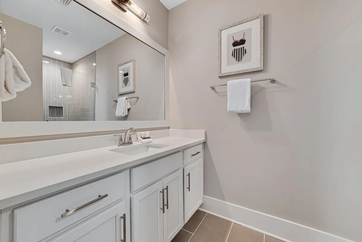 A pristine vanity area with a gleaming sink, a wide mirror, and tasteful artwork. The space is well-lit and immaculately kept, evoking serenity and a sense of hygienic self-care.