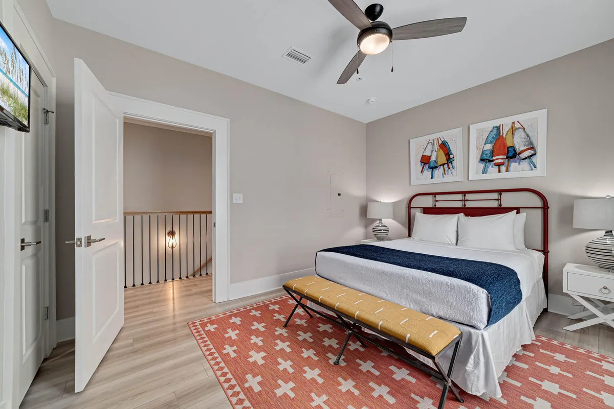A serene bedroom scene with blue and white bedding, tasteful artwork, a decorative bench, and a softly glowing bedside lamp. The space looks fresh, inviting, and immaculately prepared, conveying a sense of comfort and restful cleanliness.