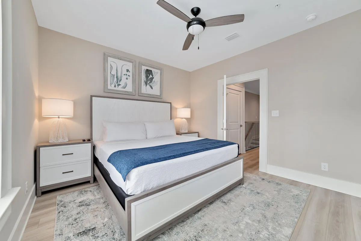A tranquil bedroom with a comfortable bed, nightstand, calming artwork, and a soft rug underfoot. The mood is peaceful, emphasizing a restful atmosphere ideal for winding down after a busy day.