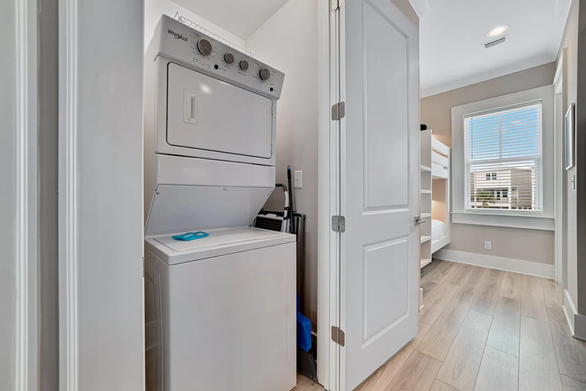A practical laundry area with a stacked washer and dryer unit, partially visible bunk beds, and a window letting in natural light. The space feels efficient yet welcoming, reflecting the comforts and conveniences provided for extended guests.